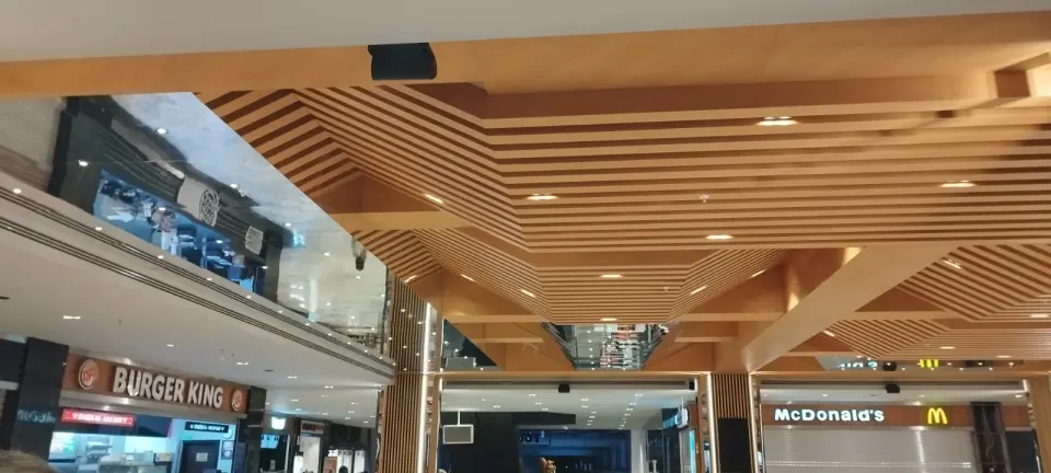 Galeri boşluğu kenarında kademeli ahşap çıtalı tavan ve altındaki restoran cepheleri