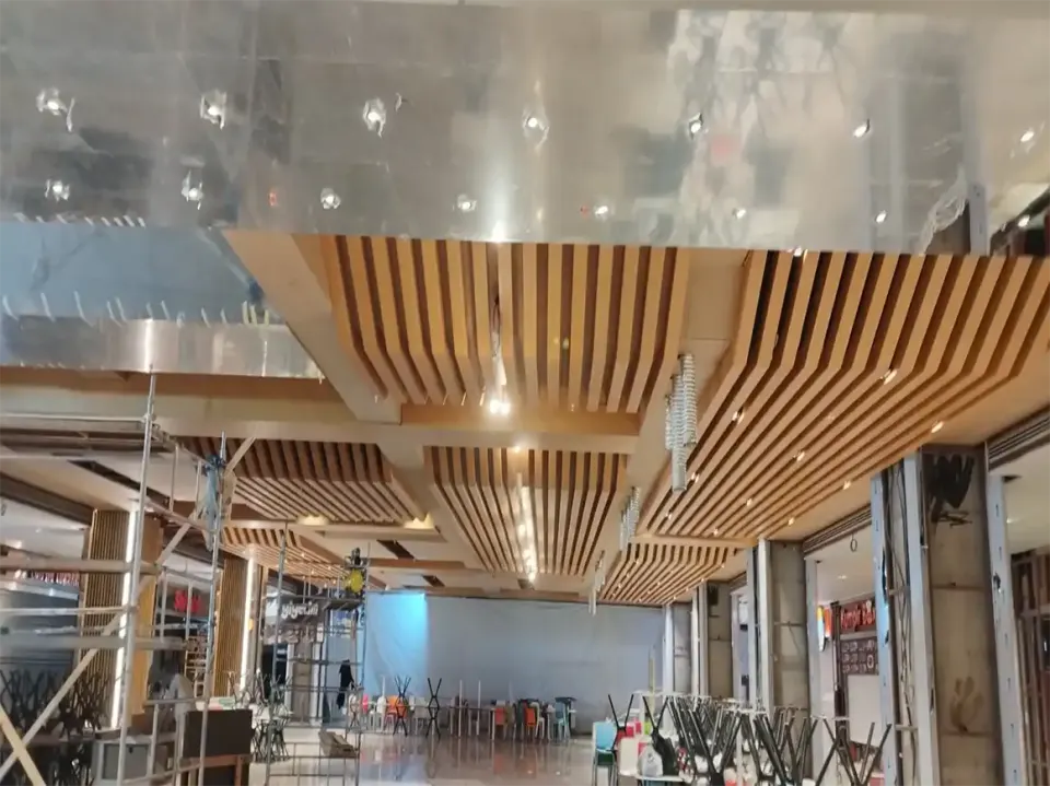 Yapım sürecindeki yemek alanında asılı ahşap çıtalar, iskele ve istiflenmiş sandalyeler